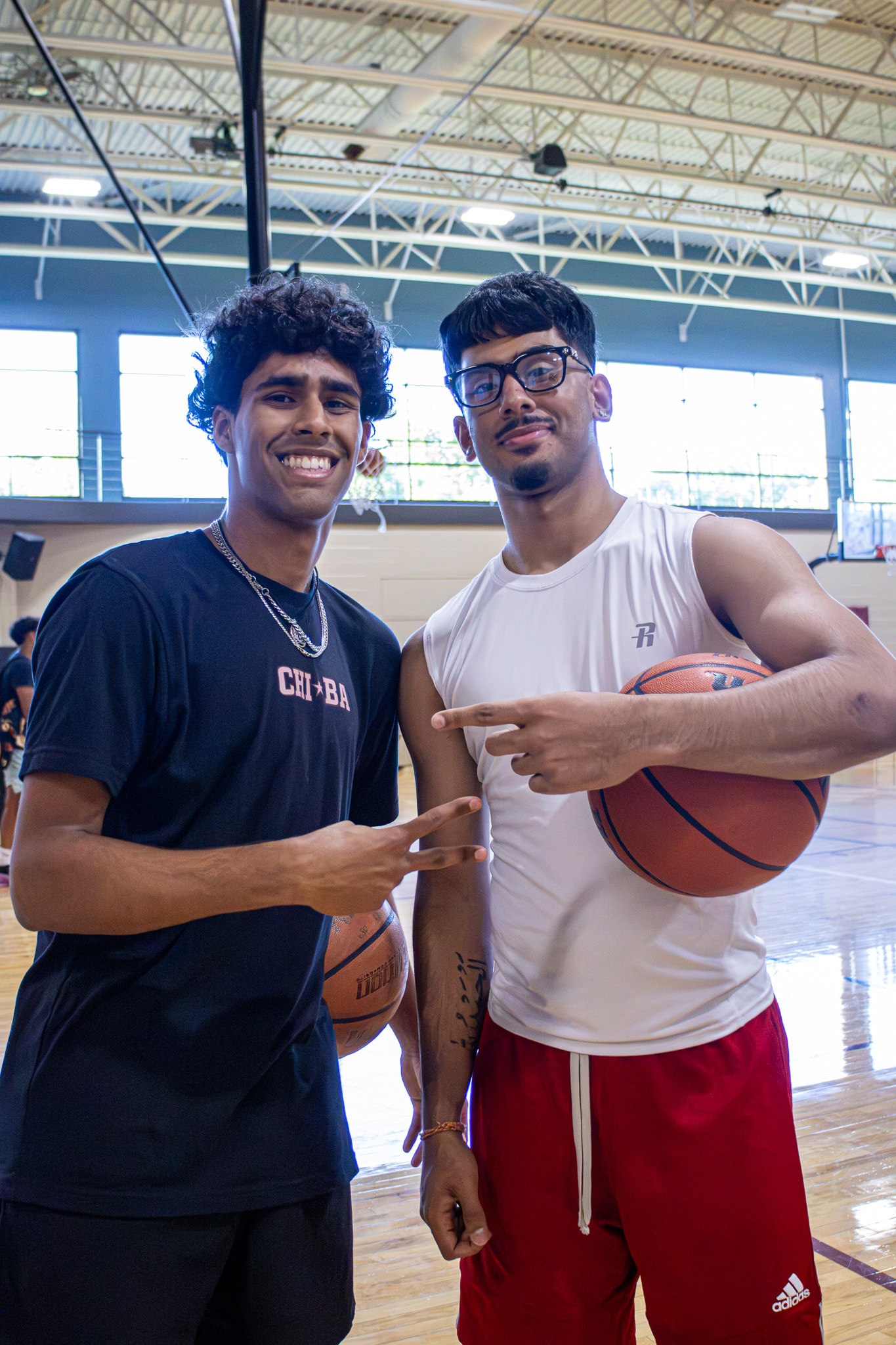 Two players posing in gym with basketballs