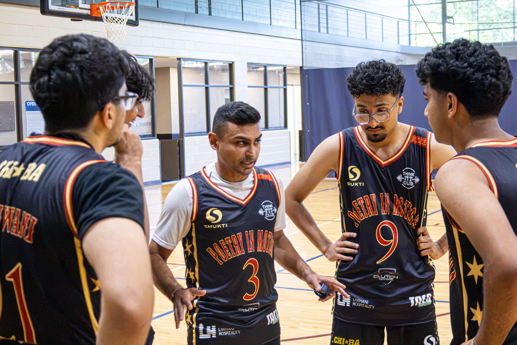 Basketball team in black red jerseys huddle